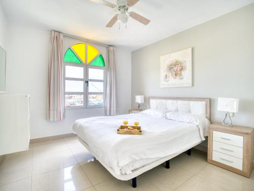 a white bedroom with a bed with a tray of oranges on it at Marina nº 5 in Puerto de Mogán