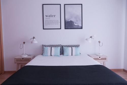 a bedroom with a large bed with two lamps at 4 Elements Apartment in Peniche