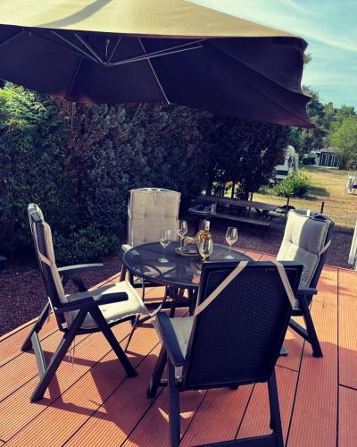 a table and chairs on a deck with an umbrella at Heerlijk bos chalet met ongekende rust en vrijheid in Nunspeet