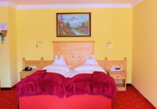 バートライヘンハルにあるKurhotel Schlossberghof Marzollのベッドルーム1室(赤いシーツを使用した大型ベッド1台付)