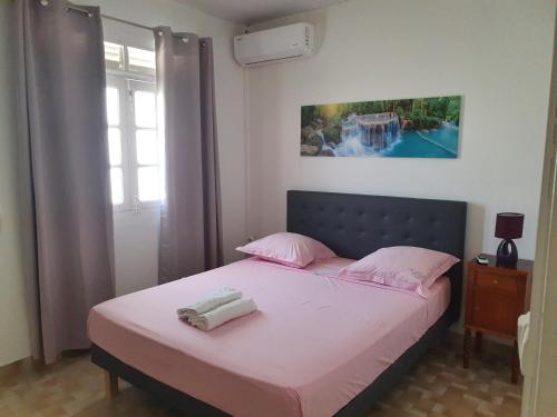een slaapkamer met een bed met roze lakens en roze kussens bij LES 4L Caïmite in Le Carbet