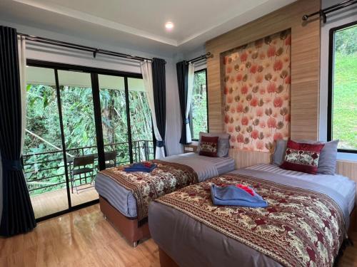 two beds in a room with large windows at Khaosok Rainforest Resort in Khao Sok National Park