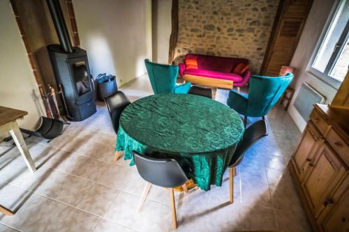 a green table and chairs in a room with a stove at Gîte Broussas Beach lac de Vassivière in Faux-la-Montagne