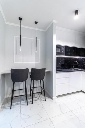 a white kitchen with two chairs and a counter at Apartament LUNA, Piotrkowska 44 - free parking in Łódź