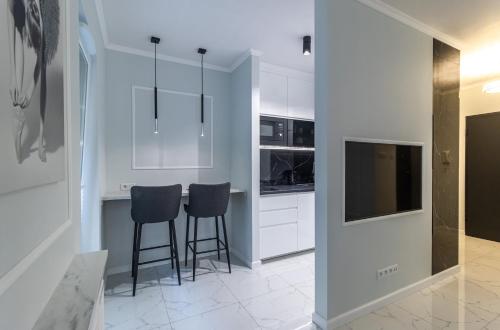 a kitchen with white cabinets and stools at Apartament LUNA, Piotrkowska 44 - free parking in Łódź