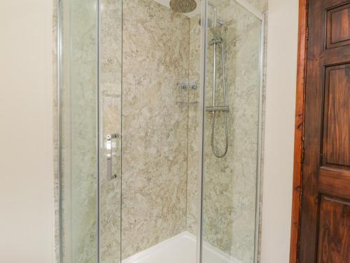 a shower with a glass door in a bathroom at Raygill Cottage in Whitby