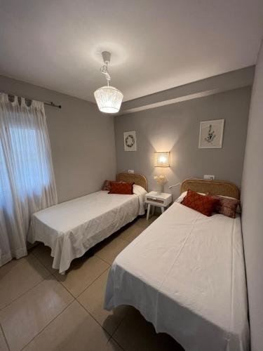 a bedroom with two beds and a chandelier at Apartamento Almar PLAYA DE LEVANTE in Benidorm