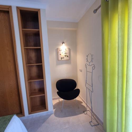 a room with a black chair and a green curtain at Casa Dos Cedros in Lagos