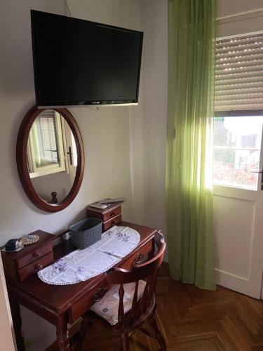 a desk with a mirror and a television on a wall at Rooms Juran in Sukošan