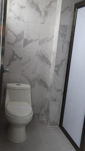 a bathroom with a toilet and a marble wall at MOTEL & HOTEL ALJIBE in Ranchito