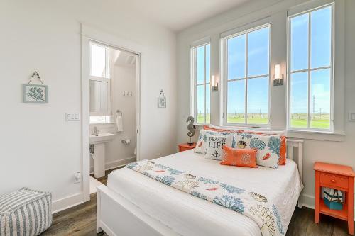a white bedroom with a bed and windows at Beach Days & Fairways in Port Aransas