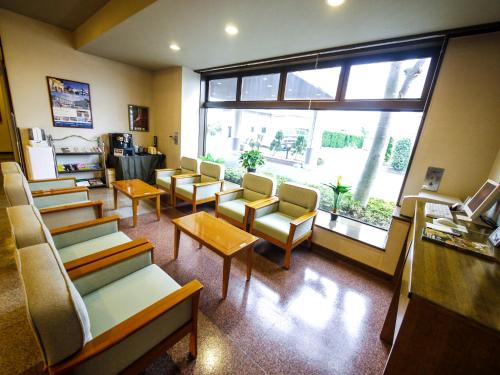 a waiting room with chairs and tables and a large window at Hotel Route-Inn Shimada Yoshida Inter in Shimada