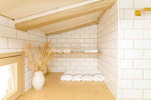baño con paredes de azulejos blancos y una fila de toallas en El Molino de Besalú Casa con jardín en Besalú
