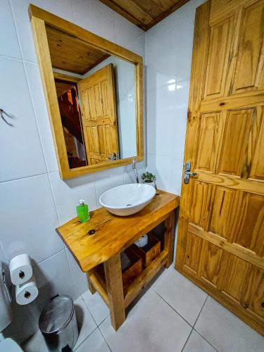 a bathroom with a sink and a mirror and a door at Pousada Recanto das Araucárias in Urubici