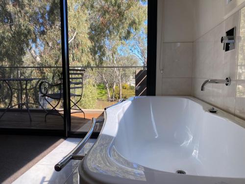 een bad in een badkamer met een groot raam bij Adelphi Apartments 3 or 3A - Downstairs 2 Bedroom or Upstairs King Studio with Balcony in Echuca