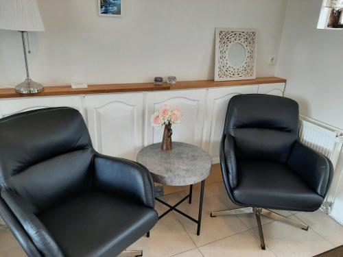 two black chairs and a table with a vase of flowers at BSG Apartments in Selfoss