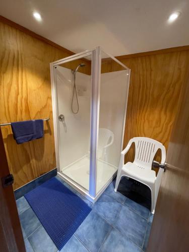 a shower with a white chair in a bathroom at Hopewell Lodge in Kenepuru Sounds