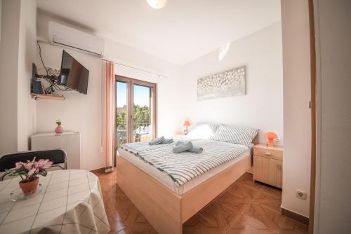 a white bedroom with a bed and a table at Apartments and rooms by the sea Vrsi - Mulo, Zadar - 5848 in Vrsi