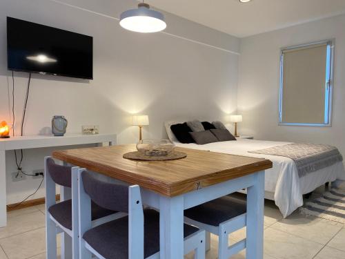 1 dormitorio con 1 cama y mesa de madera con sillas en Monoambiente Céntrico único en Puerto Madryn