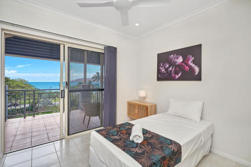 a bedroom with a bed and a balcony with the ocean at North Cove Waterfront Suites in Cairns