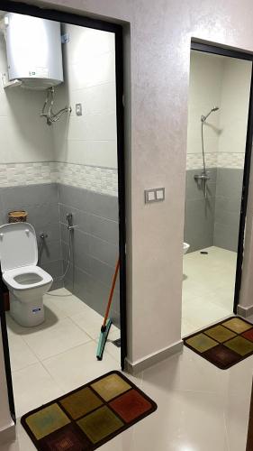 a bathroom with a toilet and two mats on the floor at Saidia Caracas AS in Saïdia