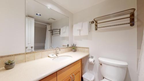 La salle de bains est pourvue d'un lavabo, de toilettes et d'un miroir. dans l'établissement Cozy 1BR, steps from Creekside Gondola by Harmony Whistler Vacations, à Whistler