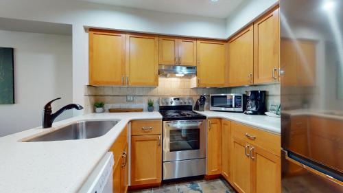 a kitchen with wooden cabinets and a sink at Cozy 1BR, steps from Creekside Gondola by Harmony Whistler Vacations in Whistler