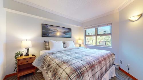 um quarto com uma cama grande e uma janela em Cozy 1BR, steps from Creekside Gondola by Harmony Whistler Vacations em Whistler