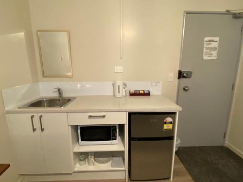 a small kitchen with a sink and a microwave at Airport Westney Lodge in Auckland
