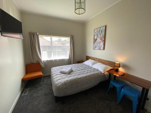 a bedroom with a bed and a desk and a window at Airport Westney Lodge in Auckland