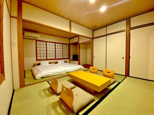 um quarto com uma cama, uma mesa e cadeiras em 外宮前別邸　星凪庵 em Ise