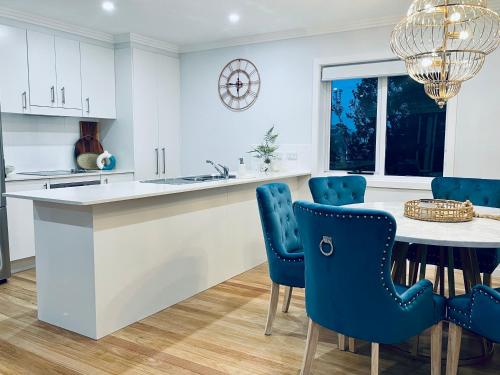 a kitchen with a table and blue chairs at Silver Beach Penthouse in Kurnell