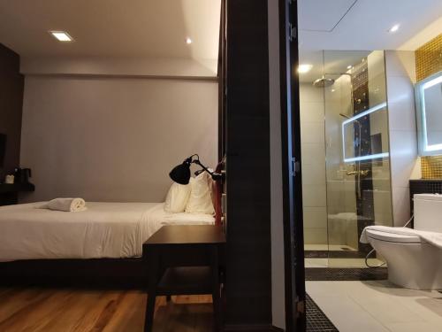 a bedroom with a bed and a bathroom with a shower at Holatel in Phitsanulok