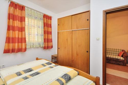 1 dormitorio con 1 cama y armario de madera en Apartment Seget Donji 10023a, en Trogir