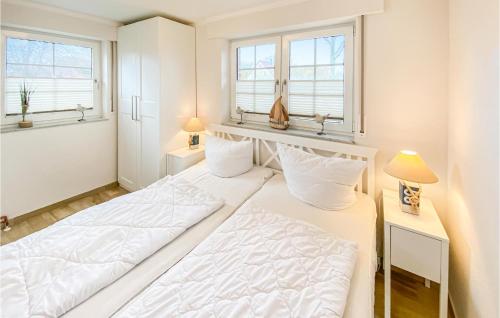 a white bedroom with two beds and two windows at Sanddorn in Gollwitz
