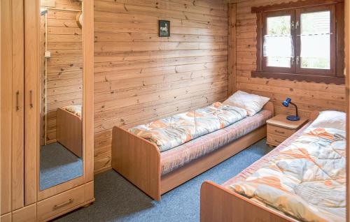 two beds in a room with wooden walls at Neska in Mścice