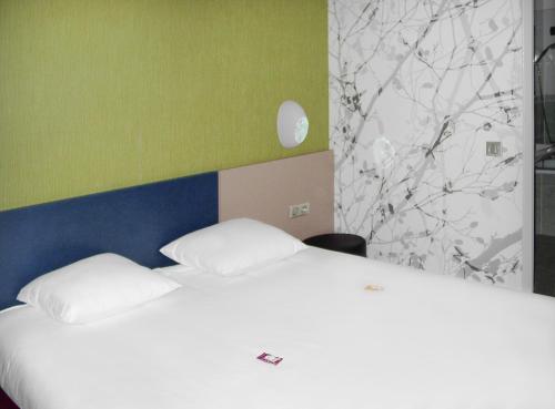 a bed with two white pillows in a room at ibis Styles Périgueux Trélissac in Trélissac