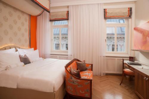 um quarto de hotel com uma cama, uma secretária e janelas em Hotel Kaiserhof Wien em Viena