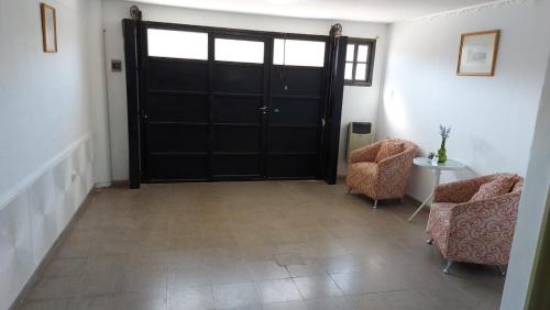 einen Flur mit schwarzer Tür und zwei Stühlen in der Unterkunft Departamento Stanza in Villa Mercedes