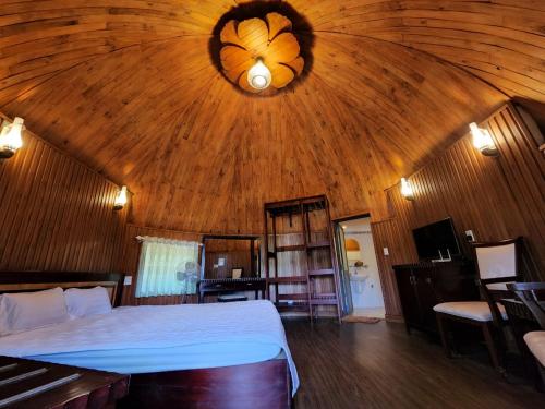 a bedroom with a large bed in a wooden ceiling at Đắk G'lung Bungalow in Bu Yal (1)