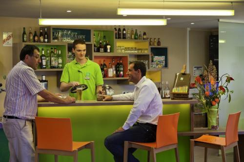 three men standing at a bar in a barber shop at ibis Styles Périgueux Trélissac in Trélissac