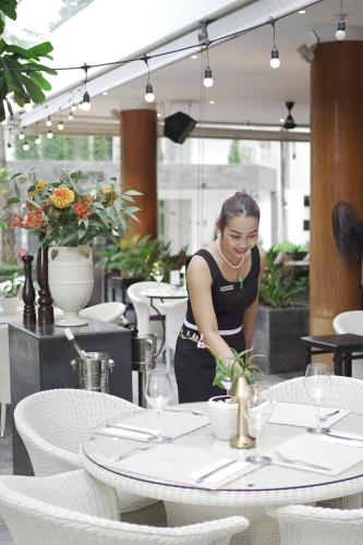a woman standing in front of a table in a restaurant at BYD Lofts - Boutique Hotel & Serviced Apartments - Patong Beach, Phuket in Patong Beach