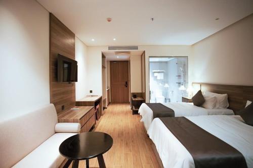Habitación de hotel con 2 camas y sofá en Win Condotel Apec Phú Yên, en Tuy Hoa