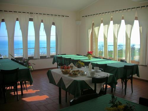 a dining room with green tables and chairs and windows at b&b Villa Eugenia in Campofilone