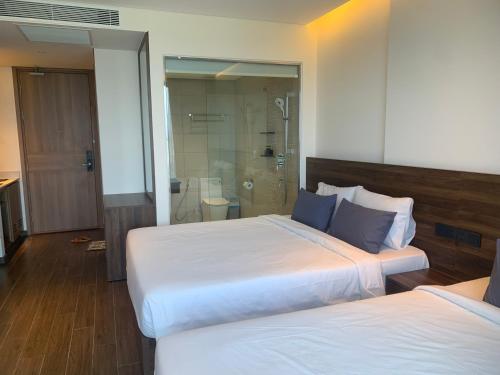a hotel room with two beds and a shower at Win Condotel Apec Phú Yên in Tuy Hoa