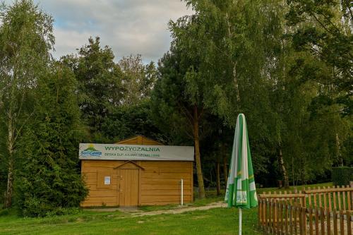 a wooden building with an umbrella and a sign at SuliCamp Kompleks Wypoczynkowy in Sulistrowice