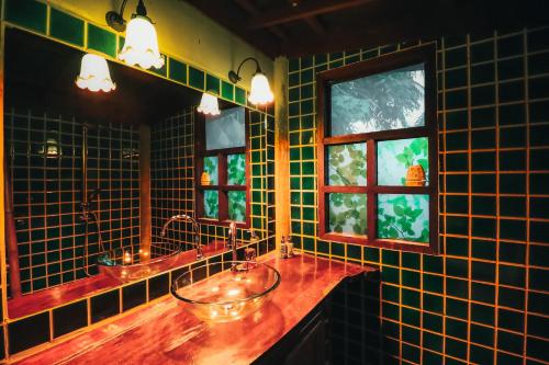 a green tiled bathroom with two sinks and two windows at Leeloo Paradise in Khanom