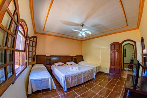 a bedroom with two beds and a ceiling fan at Pousada Casarão na Serra in Vargem Bonita