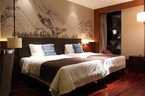 a hotel room with a large bed with blue pillows at SSAW Boutique Hotel Dexin Mogan Mountain in Deqing