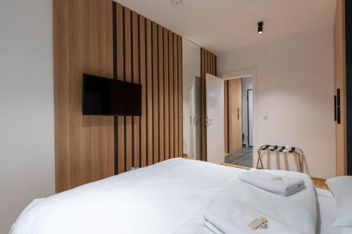 a bedroom with a white bed and a tv on a wall at President Apartman Spa in Vračar (historical)